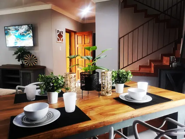 Dining table set for four beside the staircase of a duplex self-catering unit