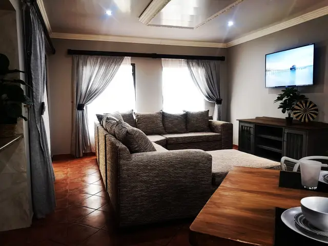 Lounge with L-shaped couch and wall-mounted TV in a Burgersfort accommodation unit