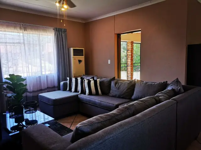 Spacious lounge with corner couch and air conditioner in a monthly rental unit